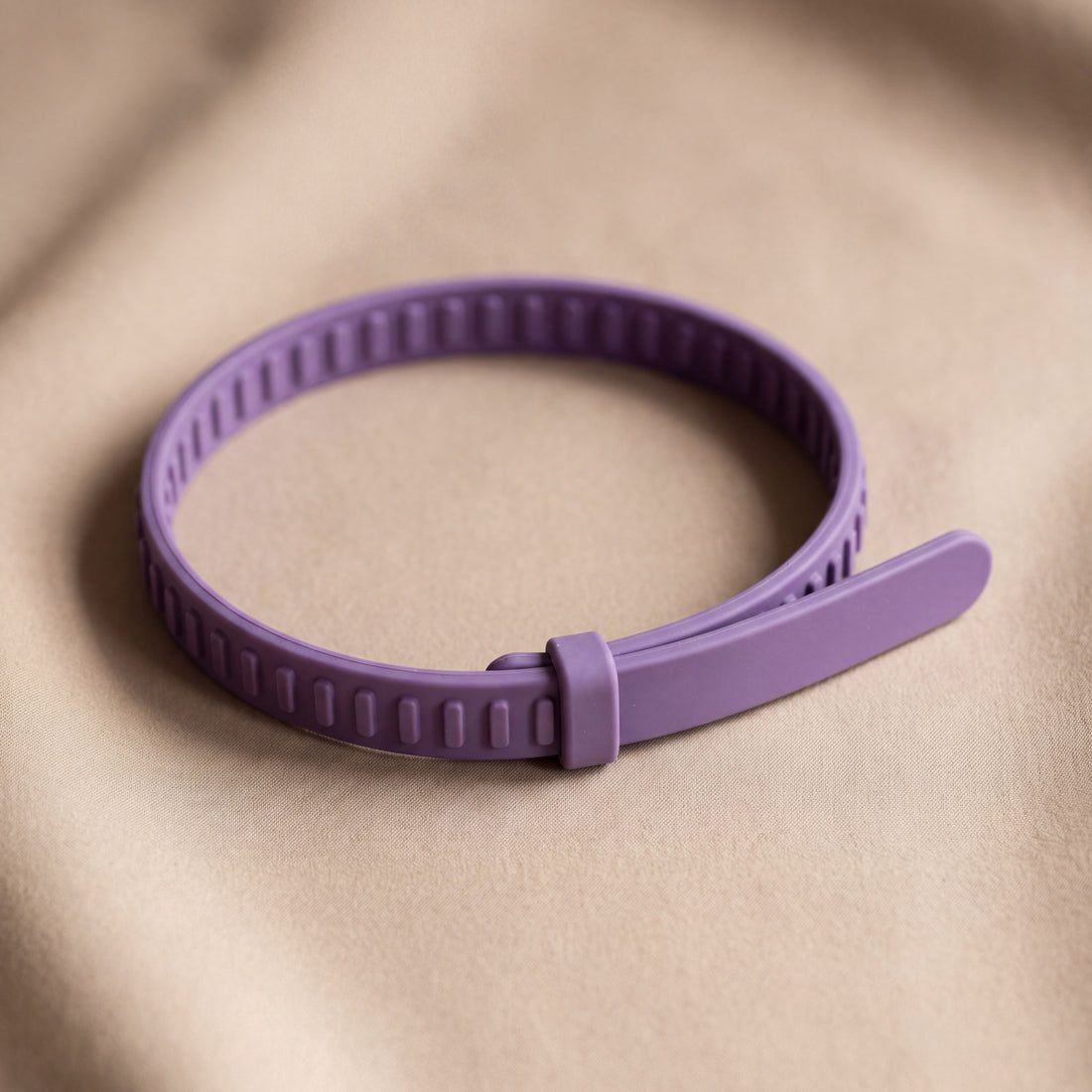 The CollarZen collar on oat linen: a notched purple TPR strap with a keeper loop and no metal buckle